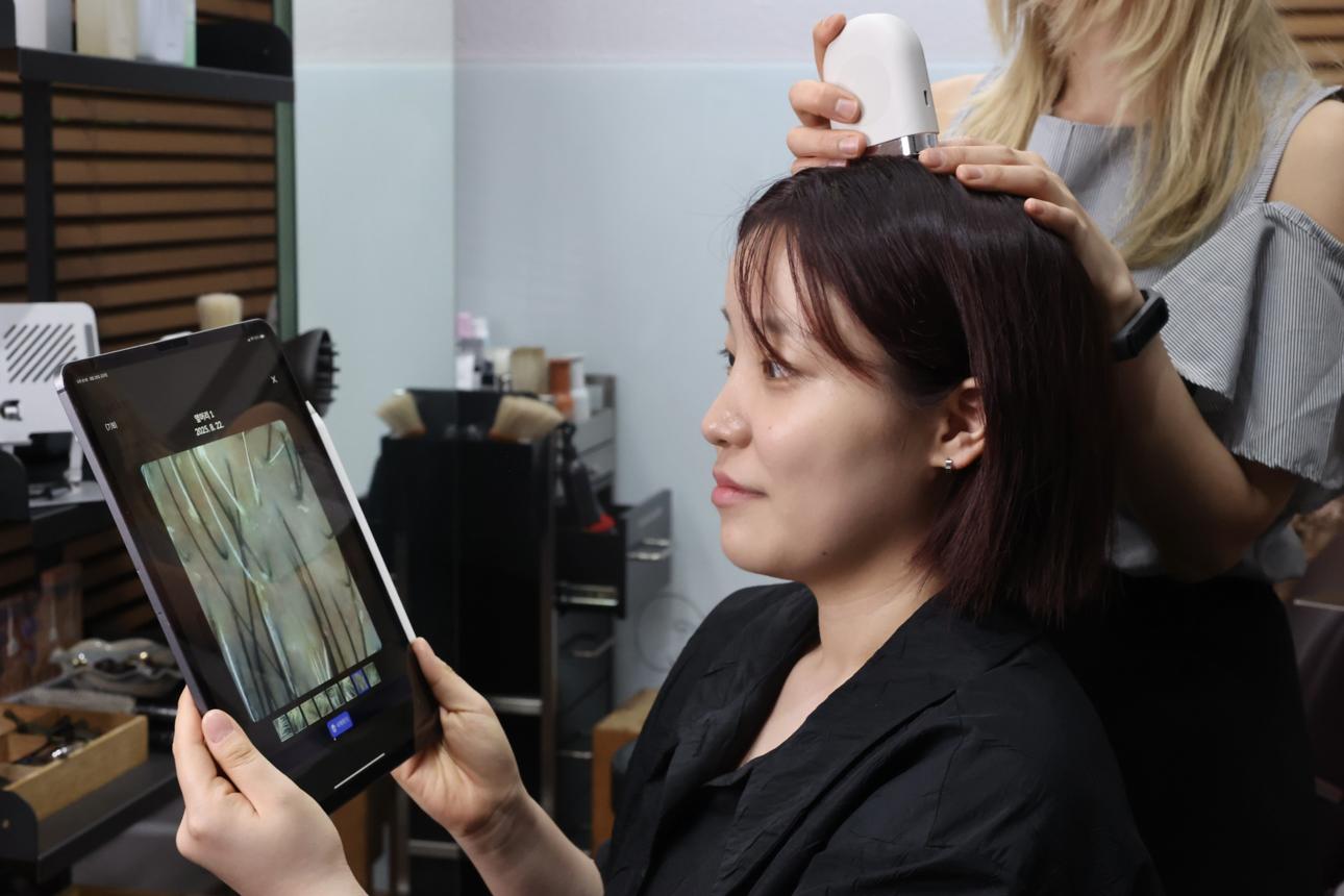 Scalp analysis during a Seoul salon head spa consultation, with magnified scalp images shown on a tablet