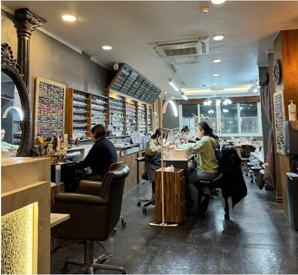 Interior of a Seoul nail salon with technicians working at stations and shelves of polish bottles lining the walls