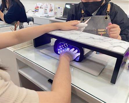 A customer's hand curing inside a UV nail lamp on a Seoul manicure table