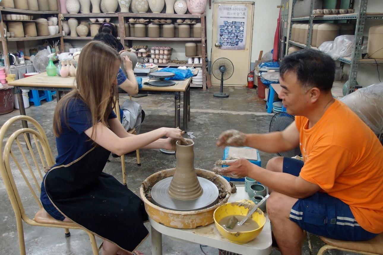 Two visitors working together at a pottery wheel in a Korean ceramic studio