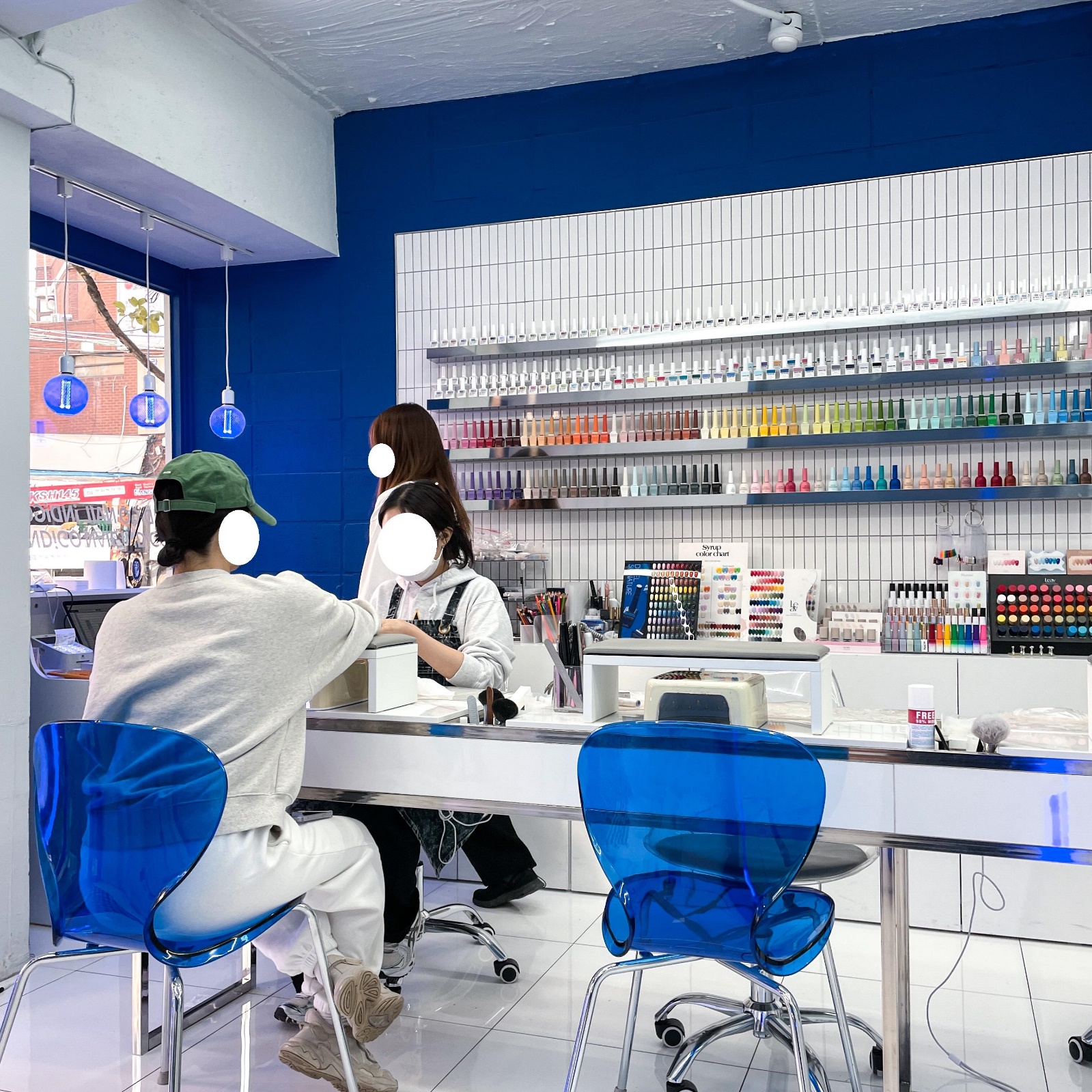 Bright Seoul nail studio with a long manicure counter and a full wall of gel colour bottles