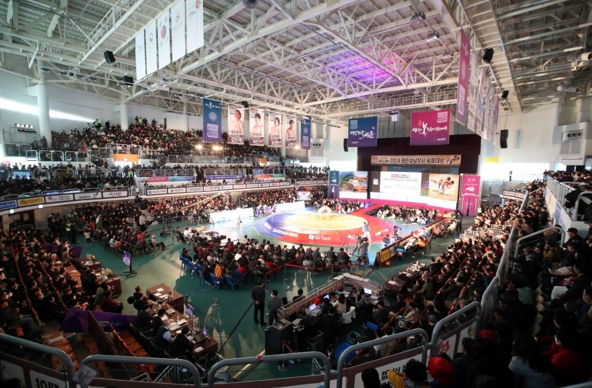 A packed indoor arena hosting a Korean traditional ssireum wrestling tournament