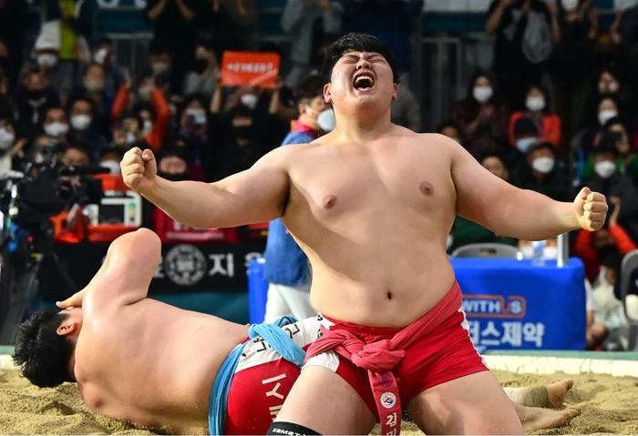A ssireum wrestler celebrating victory in the sand ring