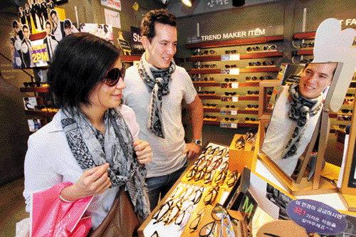 Visitors trying on sunglasses at a Korean eyewear store display