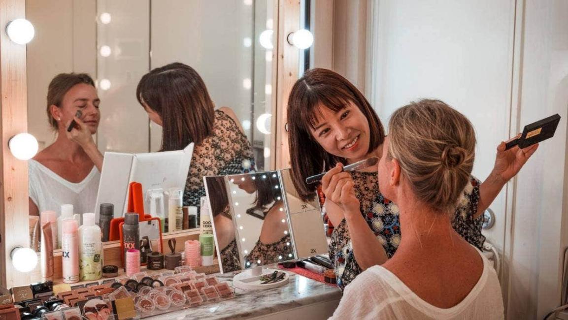International visitor learning Korean makeup at a lit vanity in a Seoul beauty studio