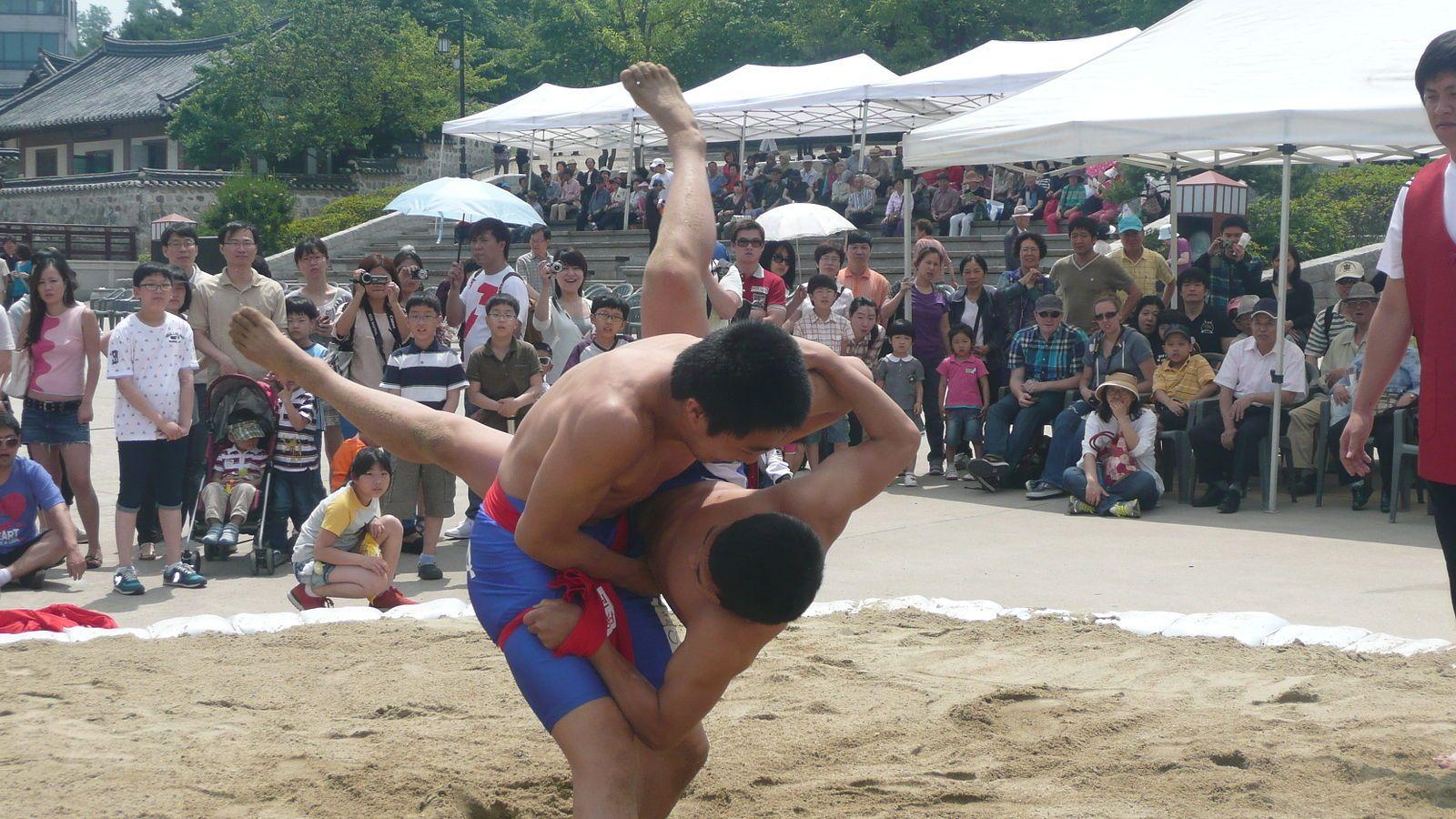 Two ssireum wrestlers competing in a traditional outdoor match on sand