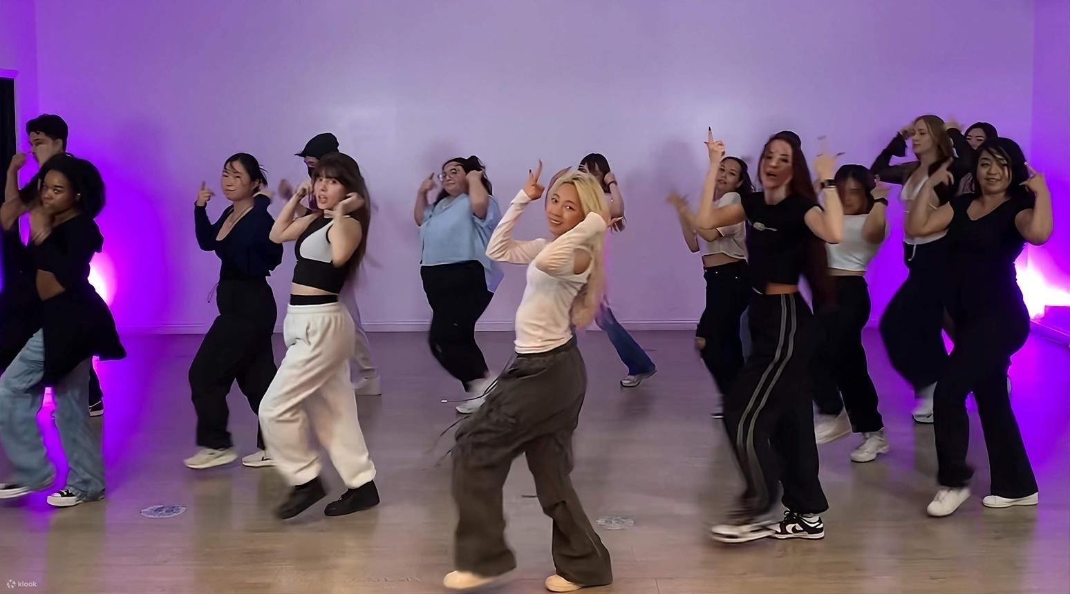 K-Pop dance class in progress in a purple-lit Seoul studio with international participants following the instructor