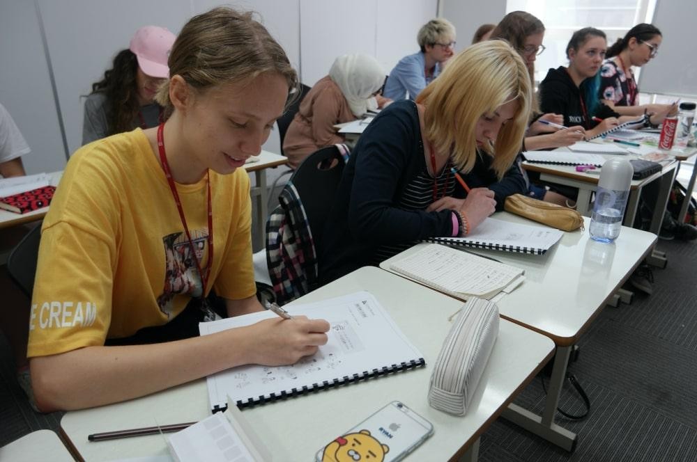 Students in a classroom setting writing in notebooks