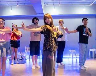 Small mixed group of international visitors learning K-Pop choreography together in a Seoul studio