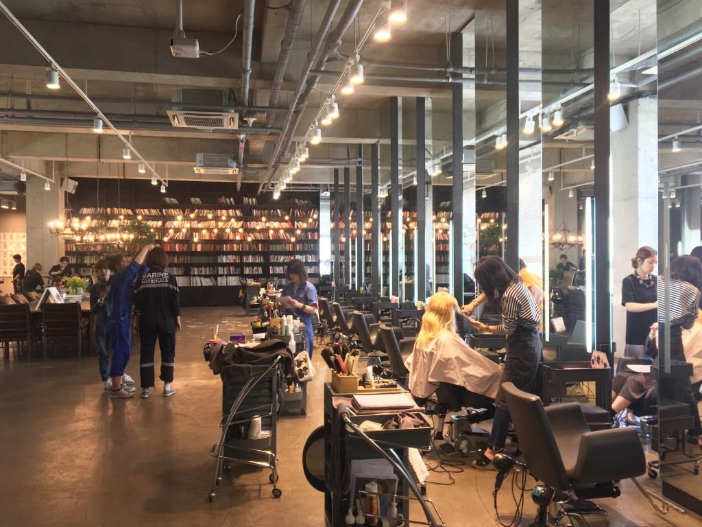 Busy open-plan Seoul hair salon with several stylists working at lit mirror stations