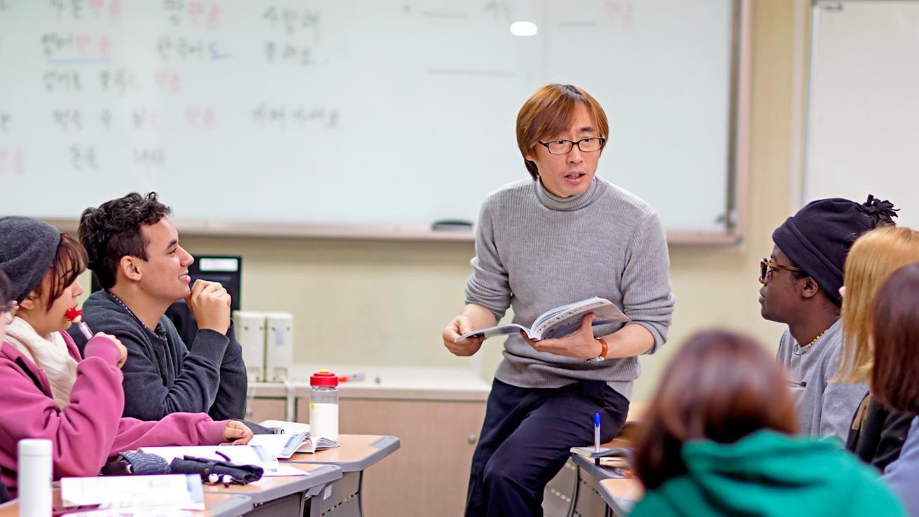 A teacher instructing a diverse group of students in a classroom setting.