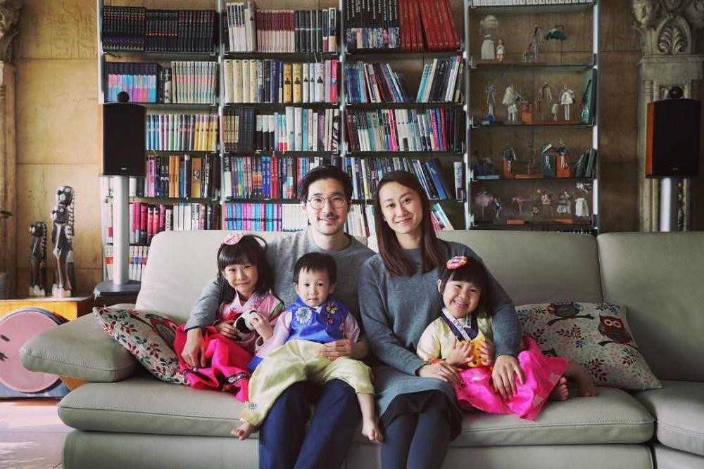 A family of five sitting on a couch in front of a large bookshelf.