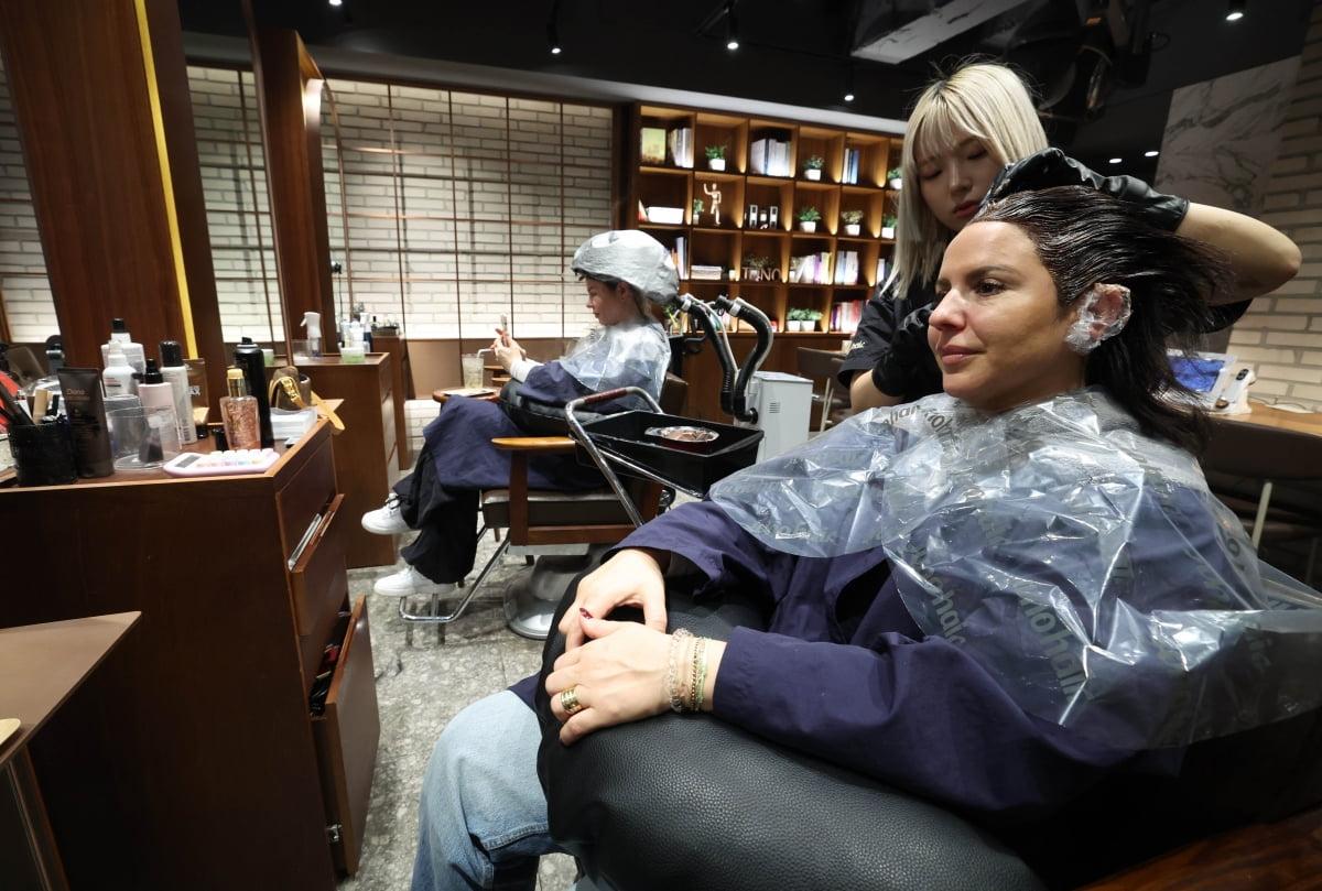 Korean stylist applying hair colour to an international customer in a Seoul salon