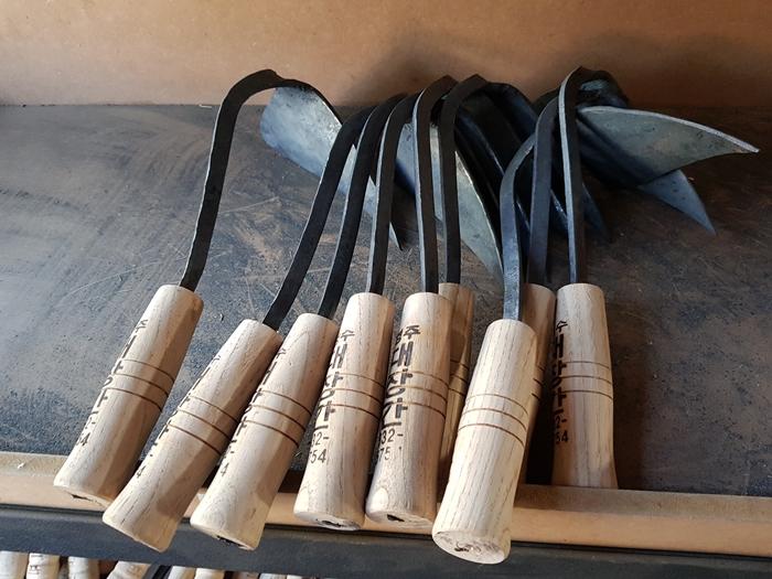A collection of hand-forged Korean tools with wooden handles