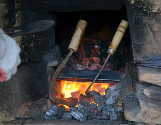 A blacksmith shaping glowing metal, showing the heating and hammering cycle of traditional forging
