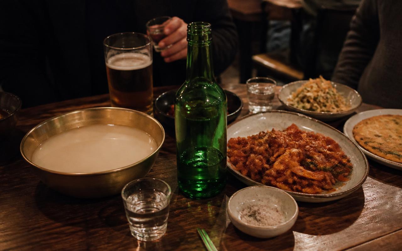 Korean pub table with soju, beer, makgeolli and shared dishes