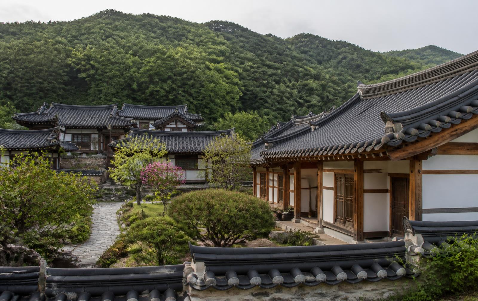 Traditional Korean wooden pavilion and earthen-walled houses beside a river in a small historic town