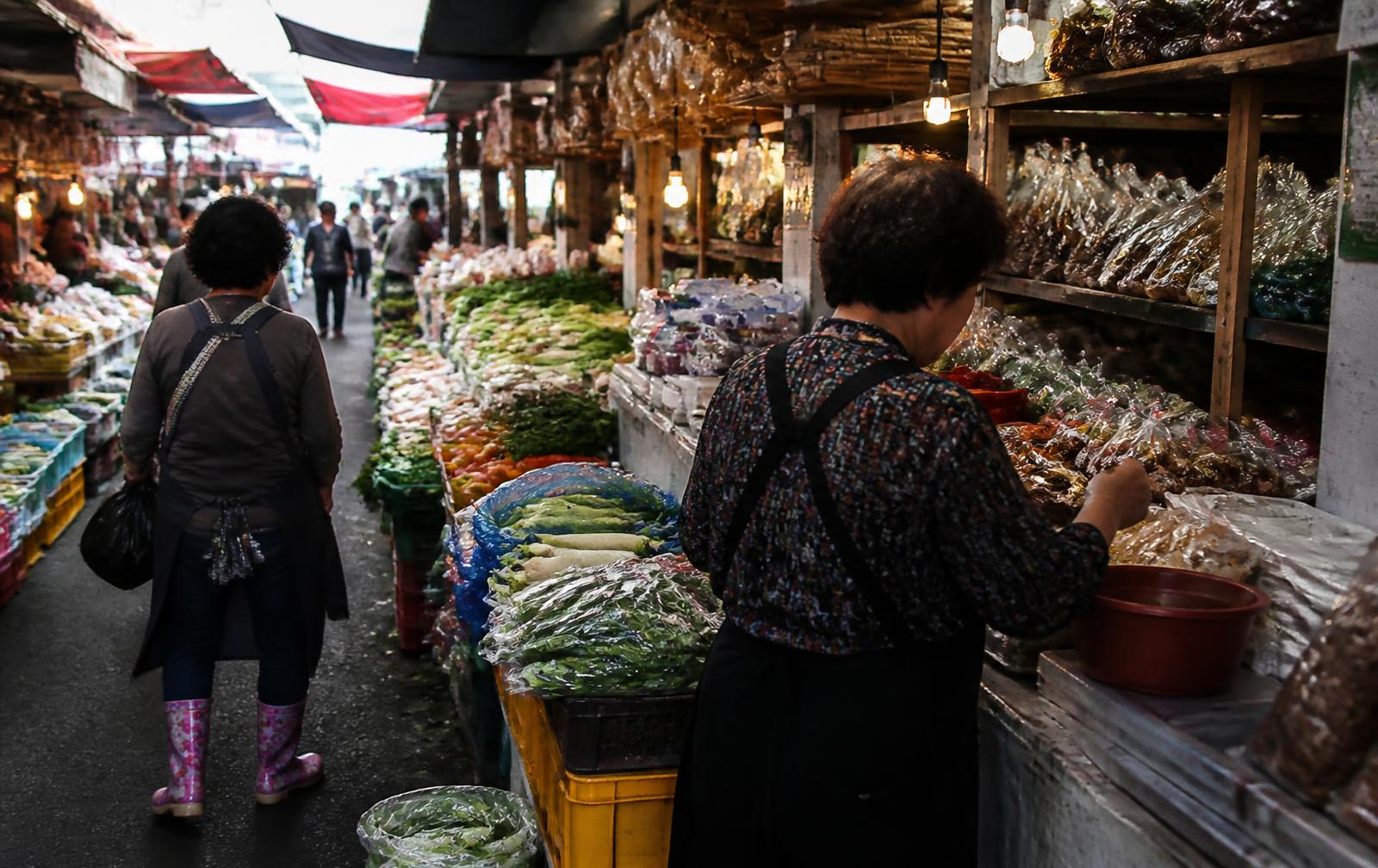 Traditional Korean market aisle with produce stalls and warm hanging lights