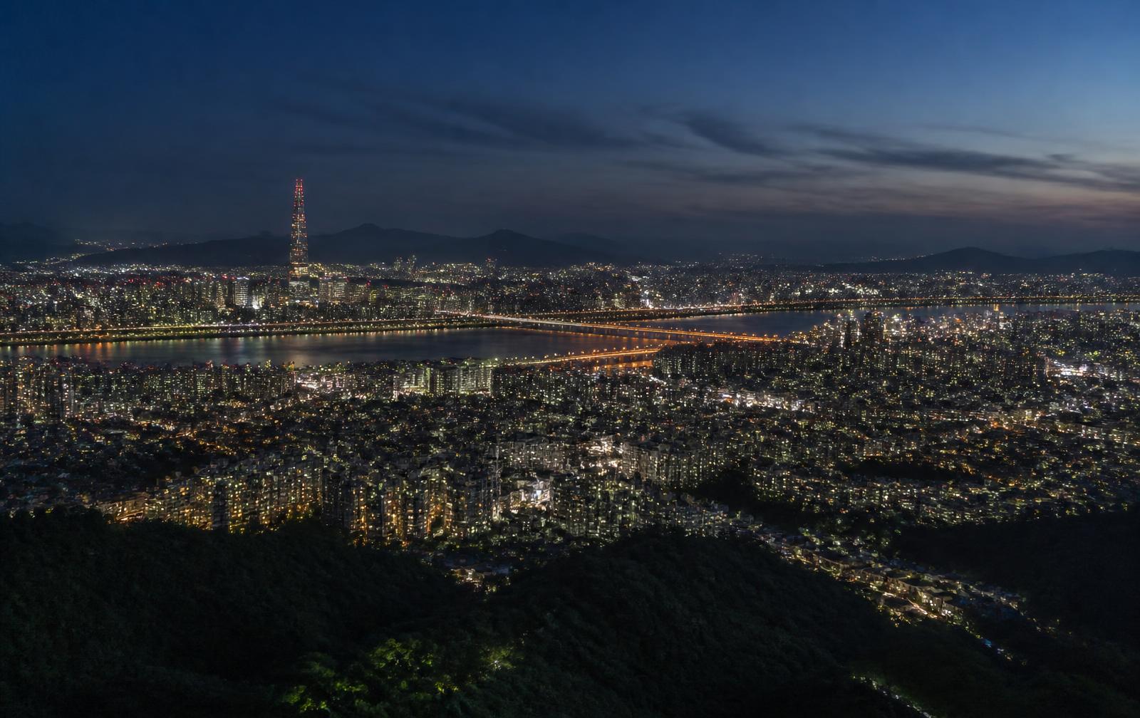 Seoul city lights, river and bridges seen from a mountain viewpoint at blue hour