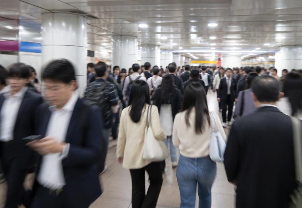 Busy commuters moving quickly through a bright Seoul subway concourse.