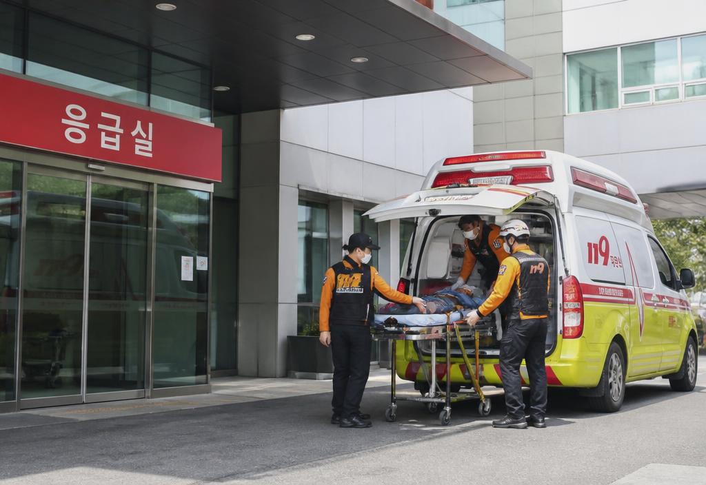 Korean emergency ambulance parked outside a modern hospital entrance in daylight.
